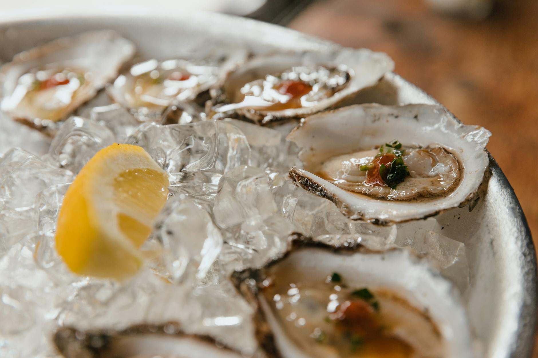 close up of fresh oysters and slice of lemon on crushed ice