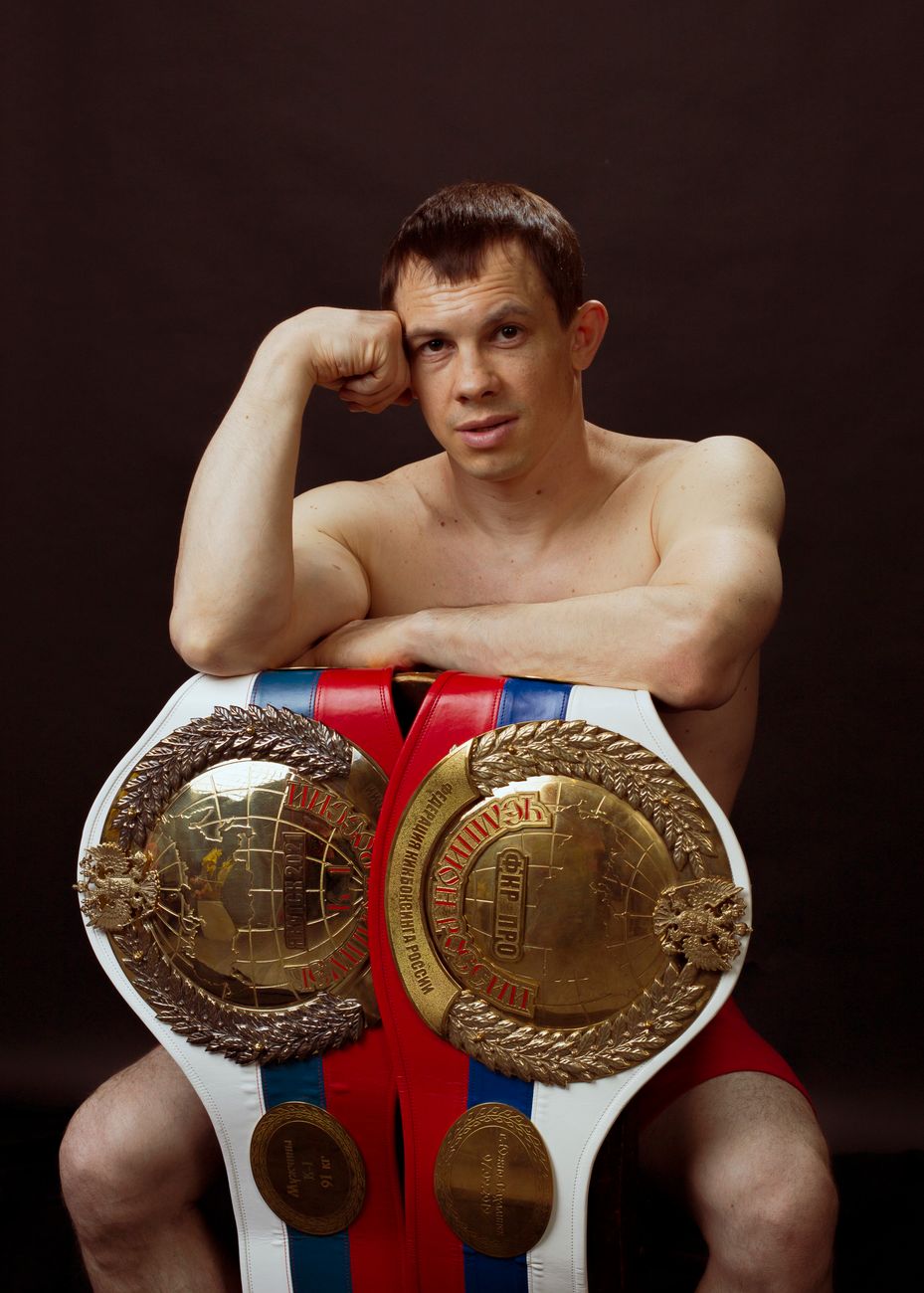 an athlete sitting with two championship belts